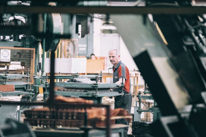 A man in a grey and red shirt operating industrial machinery in a factory