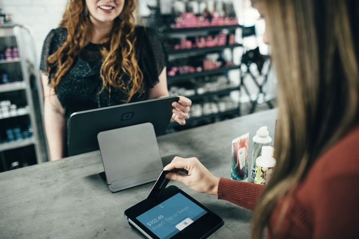 A shop owner serving a customer at the till