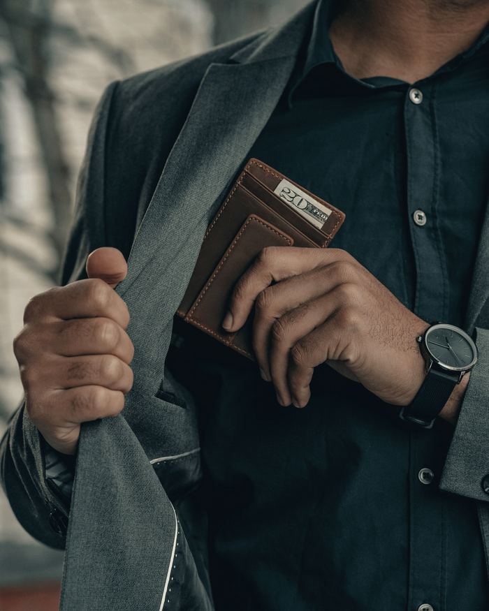 A man holding a wallet and a watch
