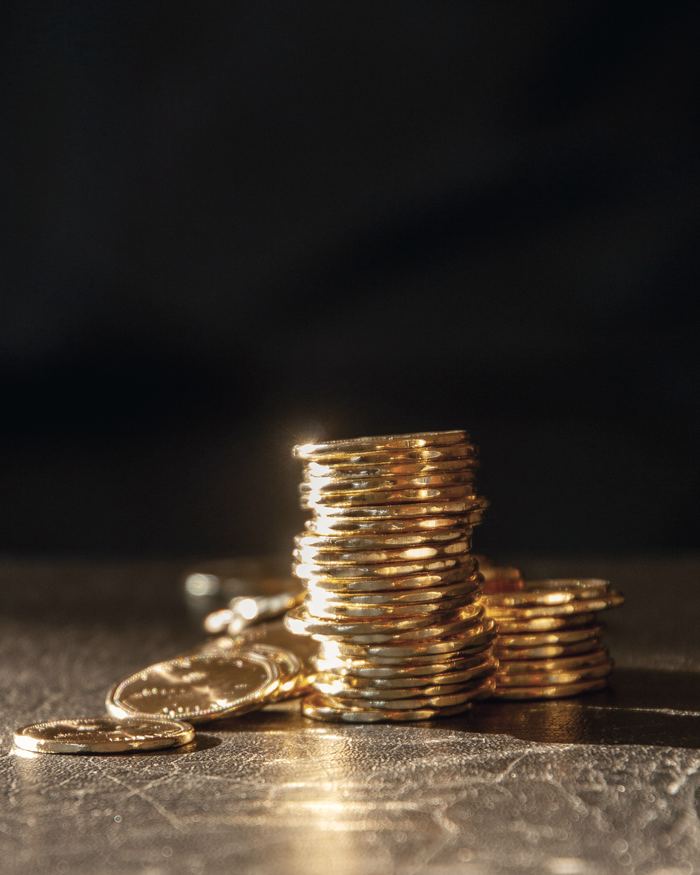 Stacks of gold coins on a dark, textured surface