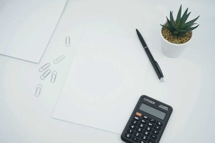 A calculator and pen on a clean white sheet of paper