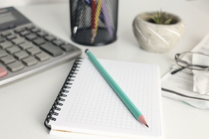 A notebook, pencil and calculator on a tidy desk