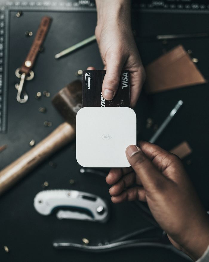 Person holding Visa card and white device