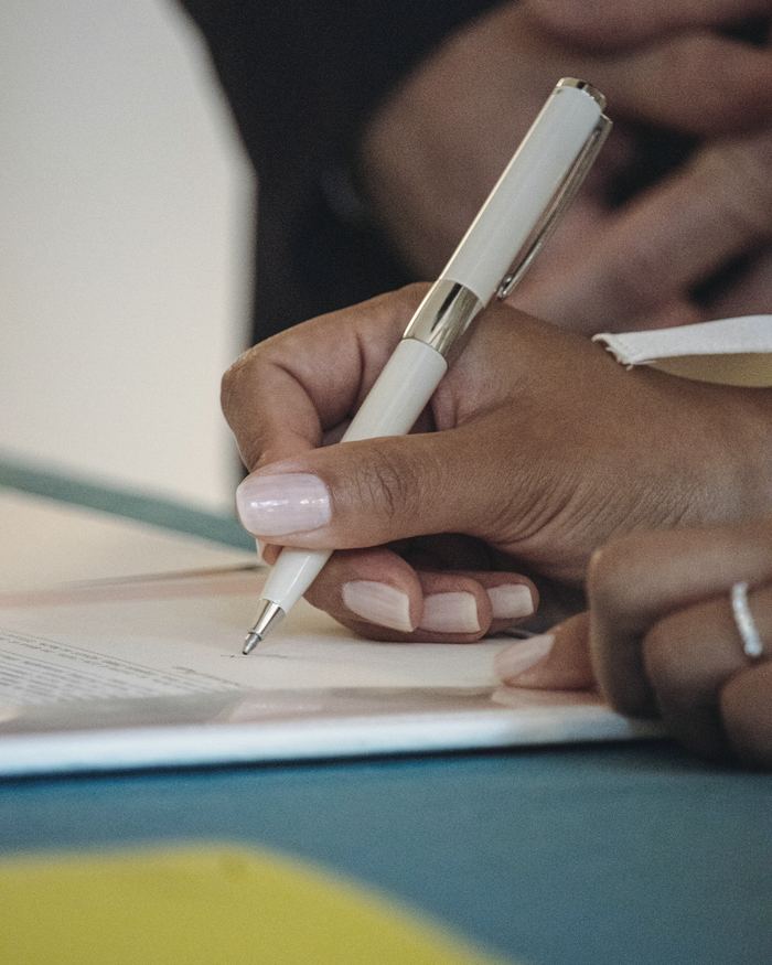 A person writing on a piece of paper with a pen