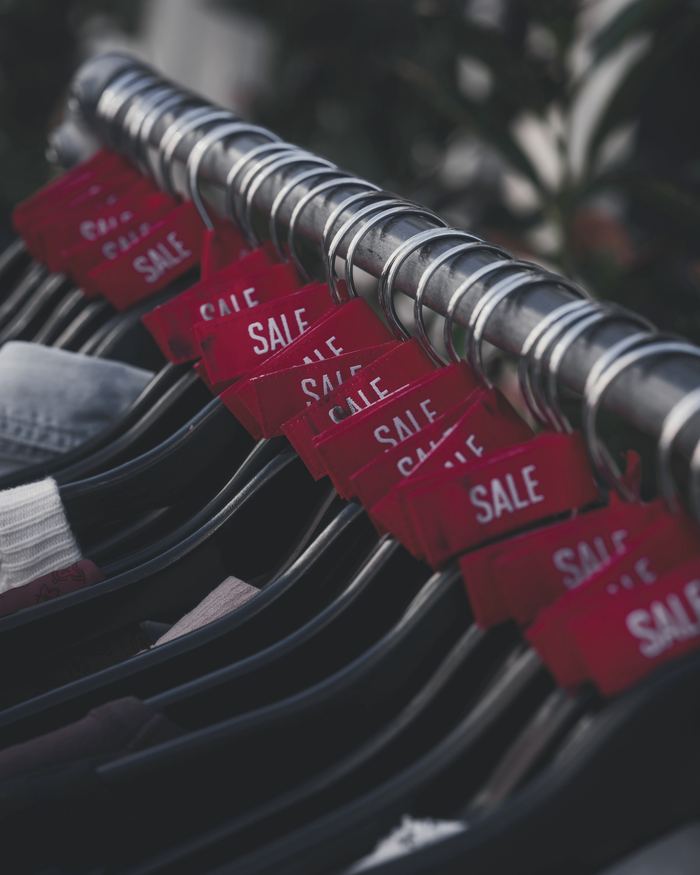Red sale tags hang on clothing racks