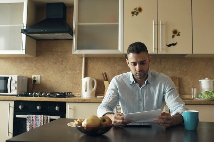 A man reading a document at his kitchen table with a coffee