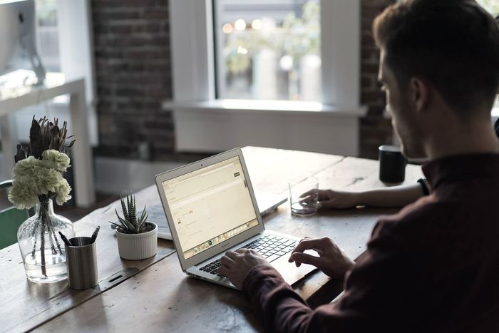 Someone working on a laptop at a table by a window