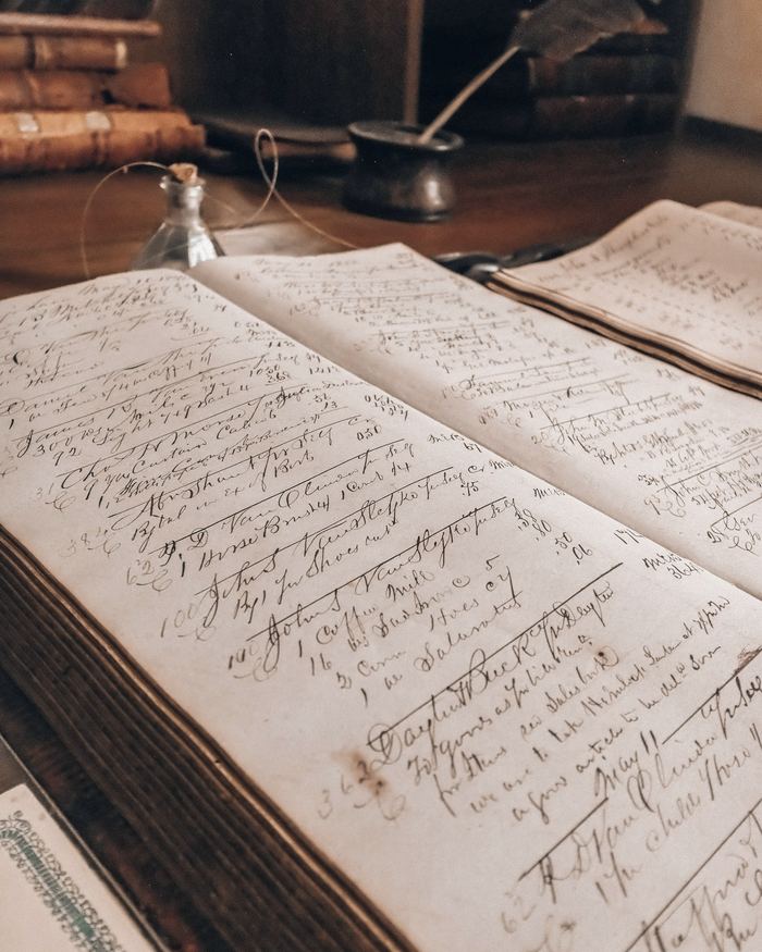 Old ledger book with handwritten entries and an inkwell