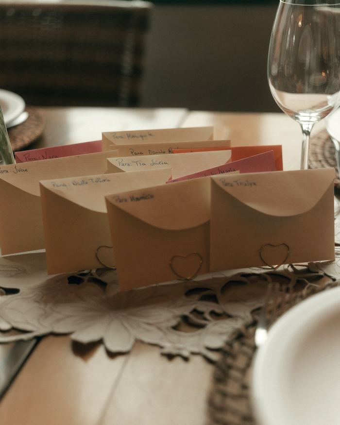 Small envelopes with handwritten names and heart-shaped clips on a dining table